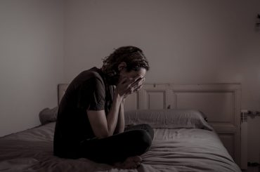 Devastated millennial man crying sad feeling hurt and hopeless suffering Depression. Depressed teenager victim of bullying or abuse sitting on bed alone in despair at night. In teenage Mental health.